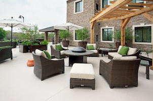 An outdoor patio area with wicker furniture, a round table, and potted plants.