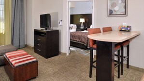 Ein Hotelzimmer mit einem Bett, einem Fernseher, einem Schreibtisch mit Stühlen, einem kleinen Tisch und einem Sofa.