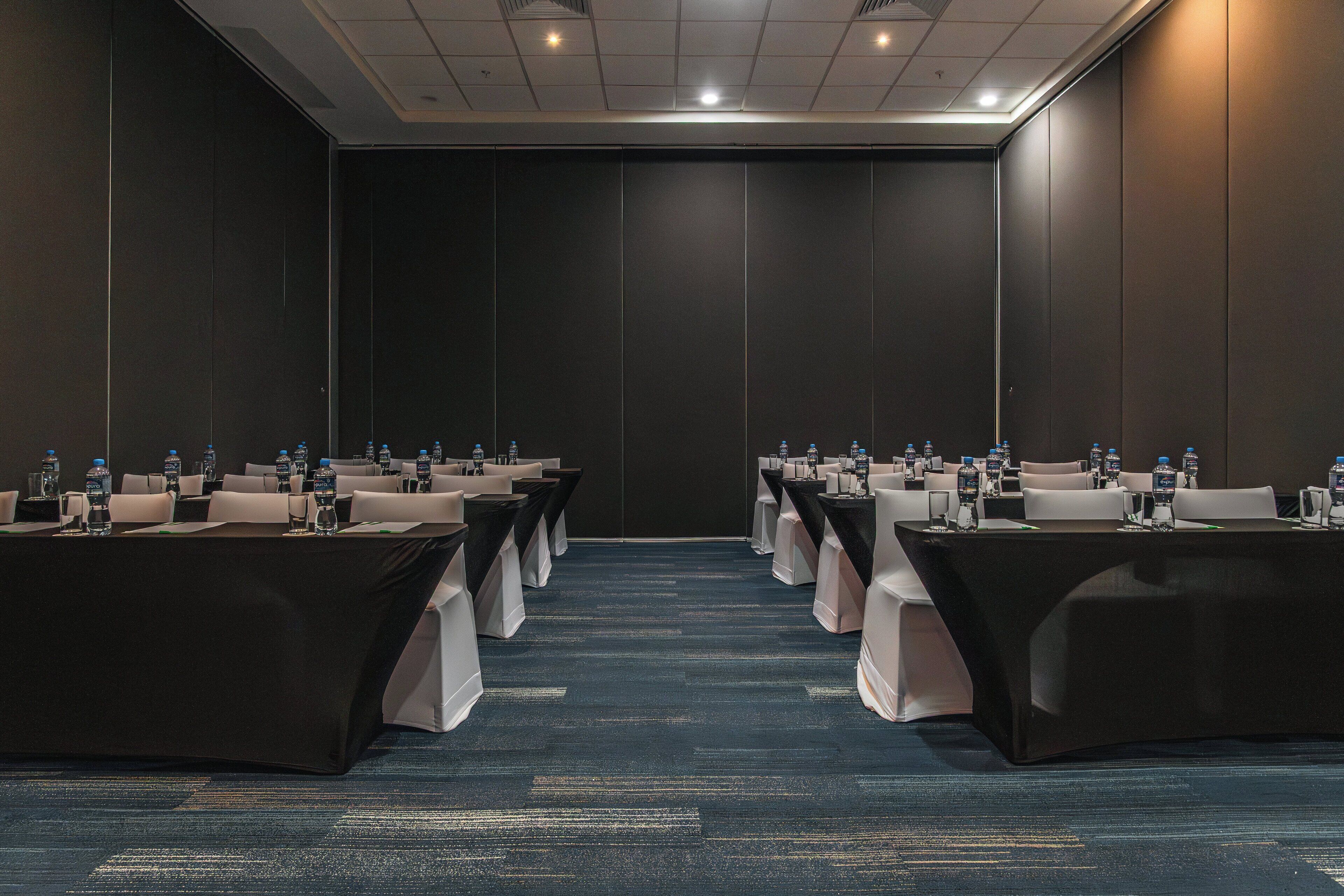 A conference room with rows of tables, each with water bottles and nameplates.