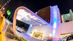 Un edificio moderno con un diseño arquitectónico único, que presenta una entrada curva y señalización iluminada.
