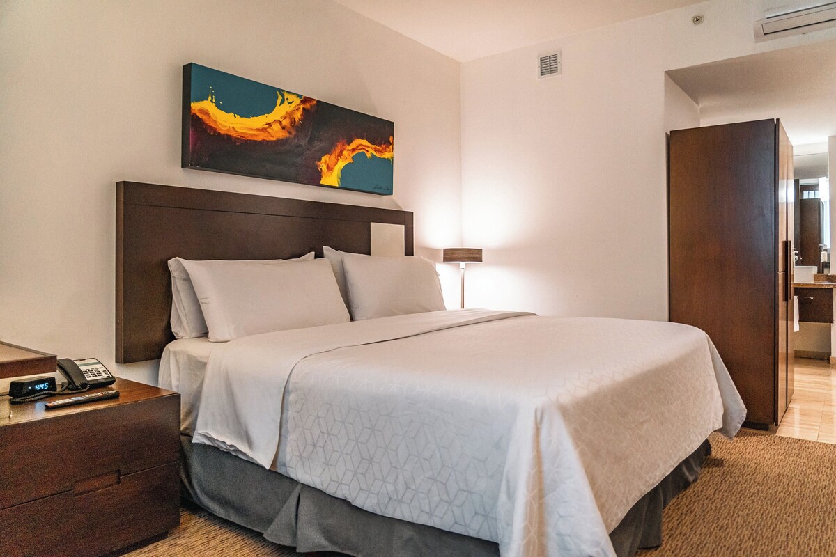 Une chambre d’hôtel avec un lit, une table de chevet et un tableau au mur.