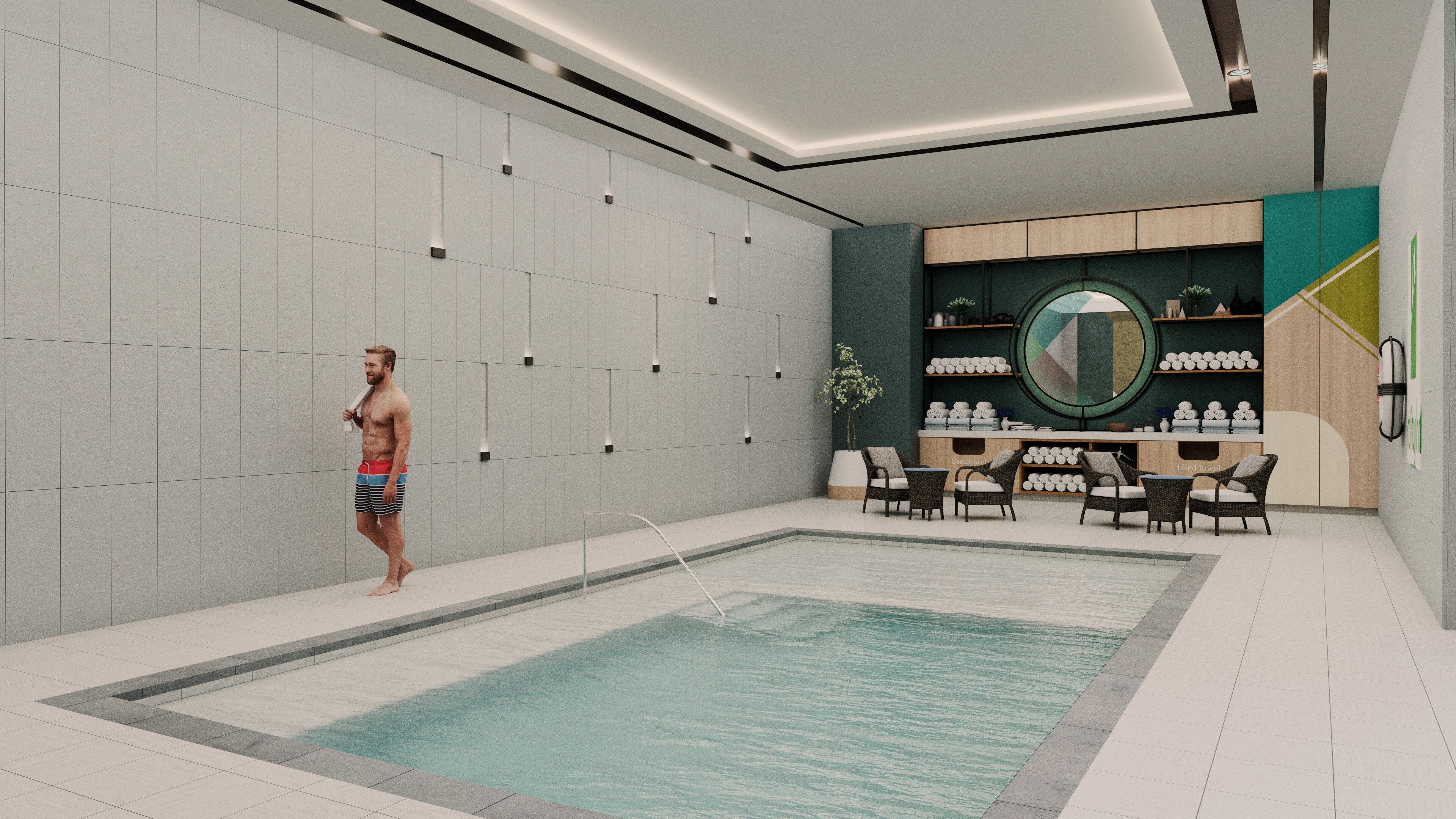 A modern indoor swimming pool with a lounge area, including seating and a display of towels.