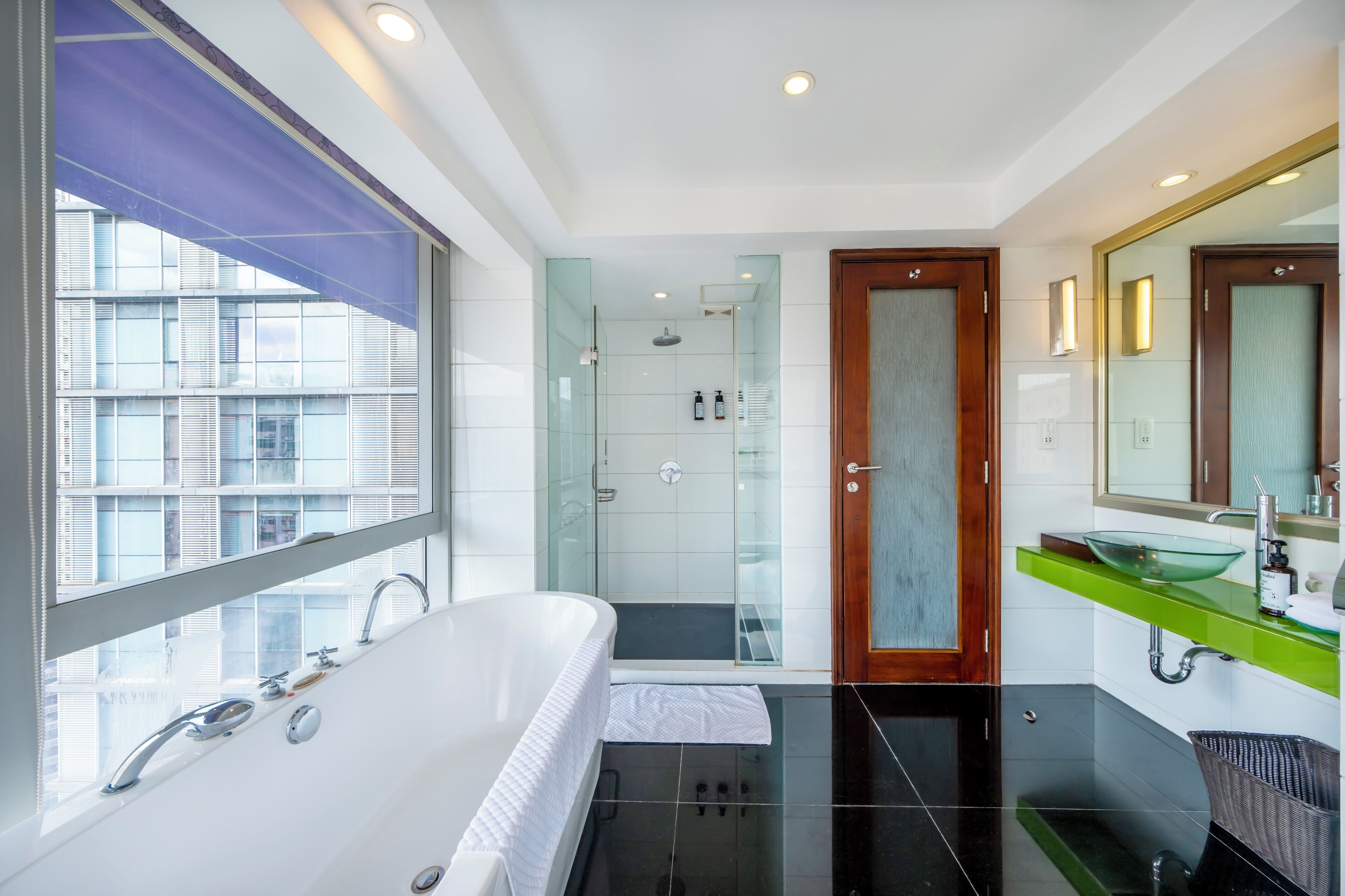 Et moderne badeværelse med et stort badekar, en brusekabine med glasvægge og et grønt toiletbord med en vask i glas.