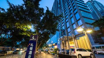 Un hotel moderno con un cartello ben visibile del Leeeden Hotel, circondato da alberi e auto parcheggiate.