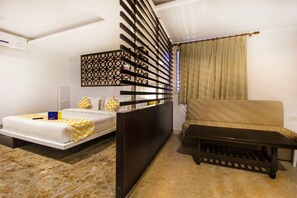 A modern bedroom with a bed, a sofa, a bench, and a decorative wall panel. - The White Klove (New Delhi)