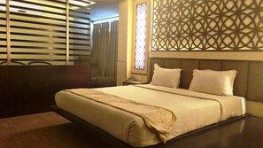 A hotel room with a large bed, a nightstand, a mirror, and a decorative wall panel. - The White Klove (New Delhi)