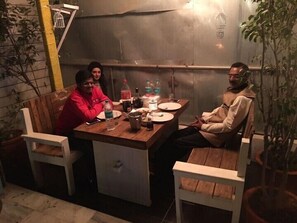 A wooden dining table with chairs, a small refrigerator, and various items on the table. - The White Klove (New Delhi)