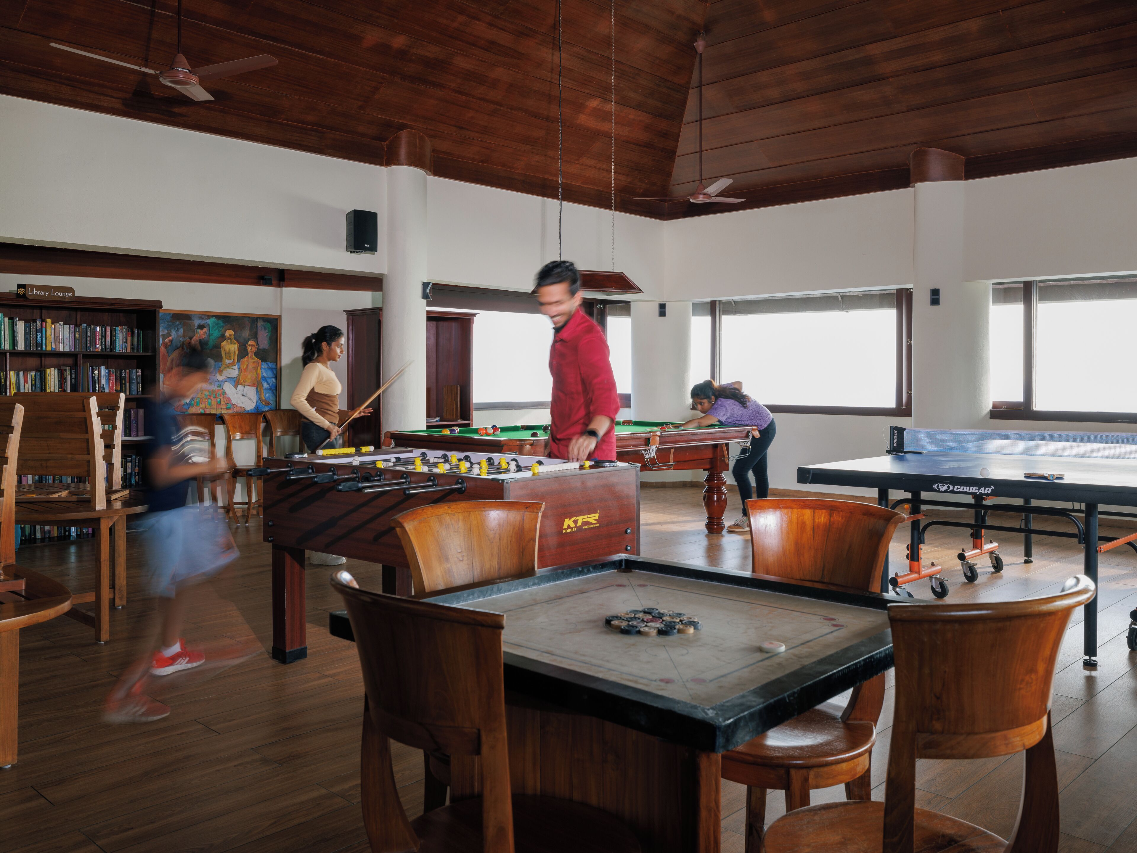 A recreational area with pool tables, foosball tables, and a billiards table.