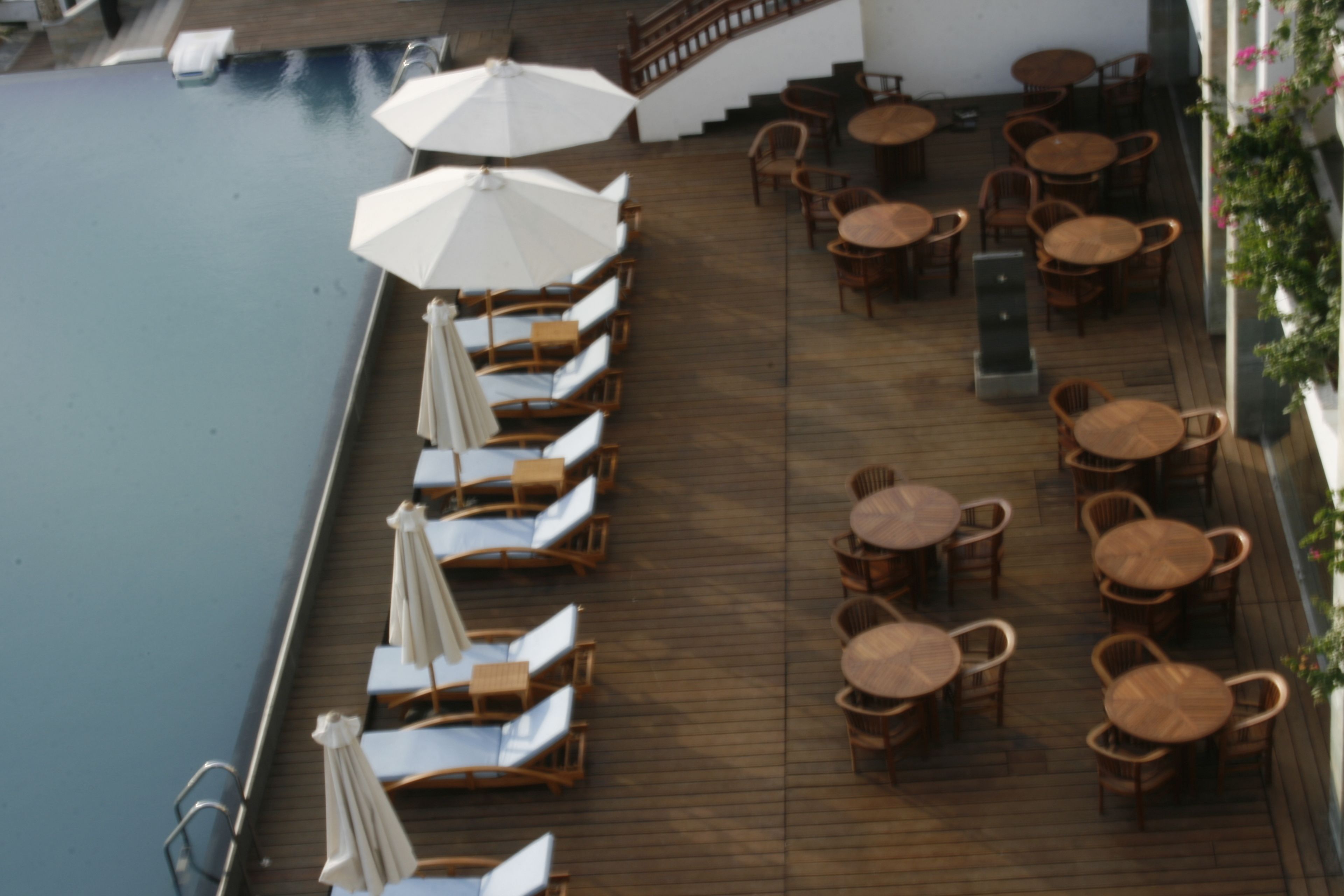 An outdoor deck with wooden flooring, lounge chairs, and tables.