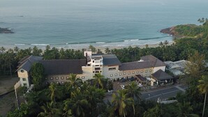 Un edificio grande de varios pisos, rodeado de palmeras y una playa.