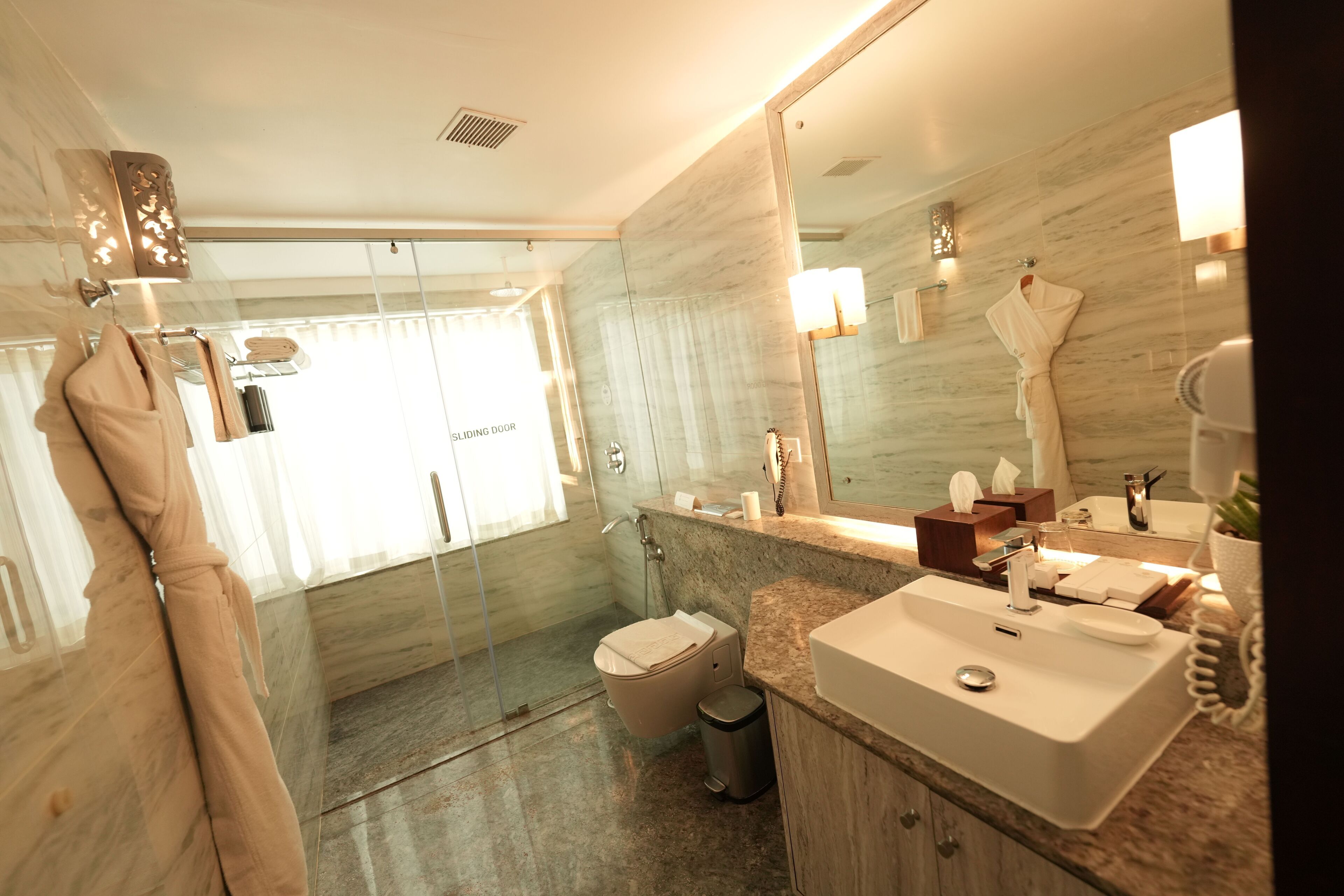 A modern bathroom with a glass shower enclosure, a white sink, and a large mirror.