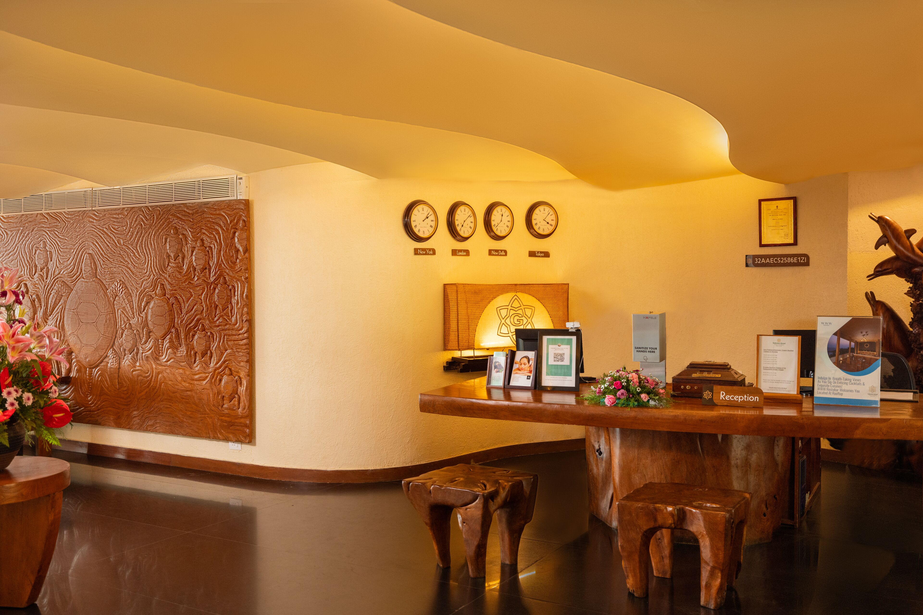 A reception area with a wooden counter, a wall clock, a framed certificate, and a reception sign.