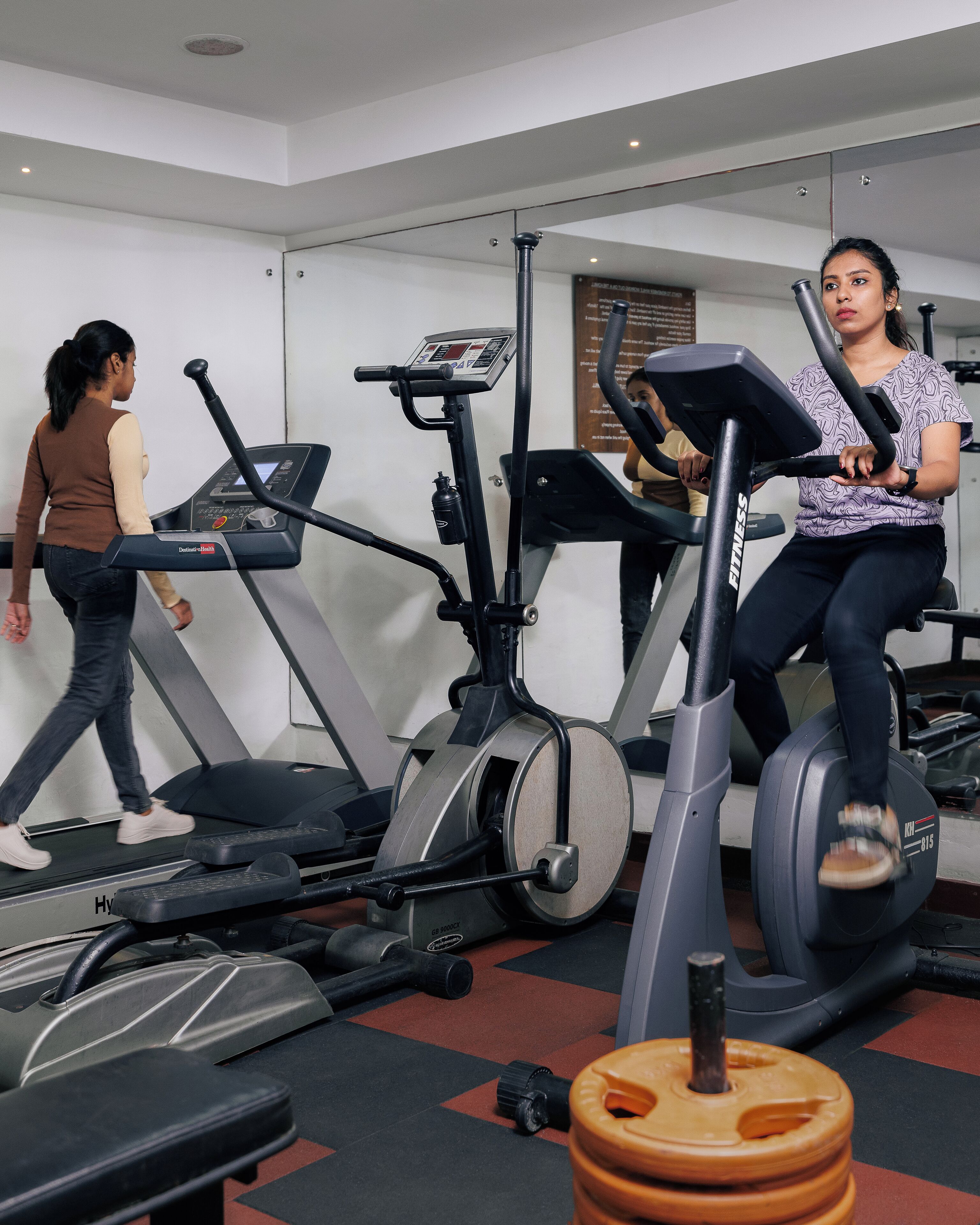 Ein Fitnessstudio mit Laufbändern, Crosstrainern und Gewichten.