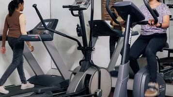 Un gimnasio con cintas de correr, elípticas y equipo de levantamiento de pesas.