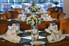 Formal dining area with a beautifully set table, featuring white napkins, glassware, and a floral centerpiece.