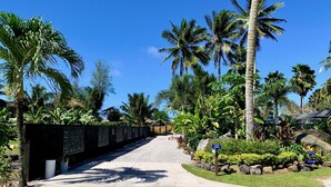 A pathway leading through a tropical resort area with palm trees and a stone wall. - Muri Beachcomber (Rarotonga)