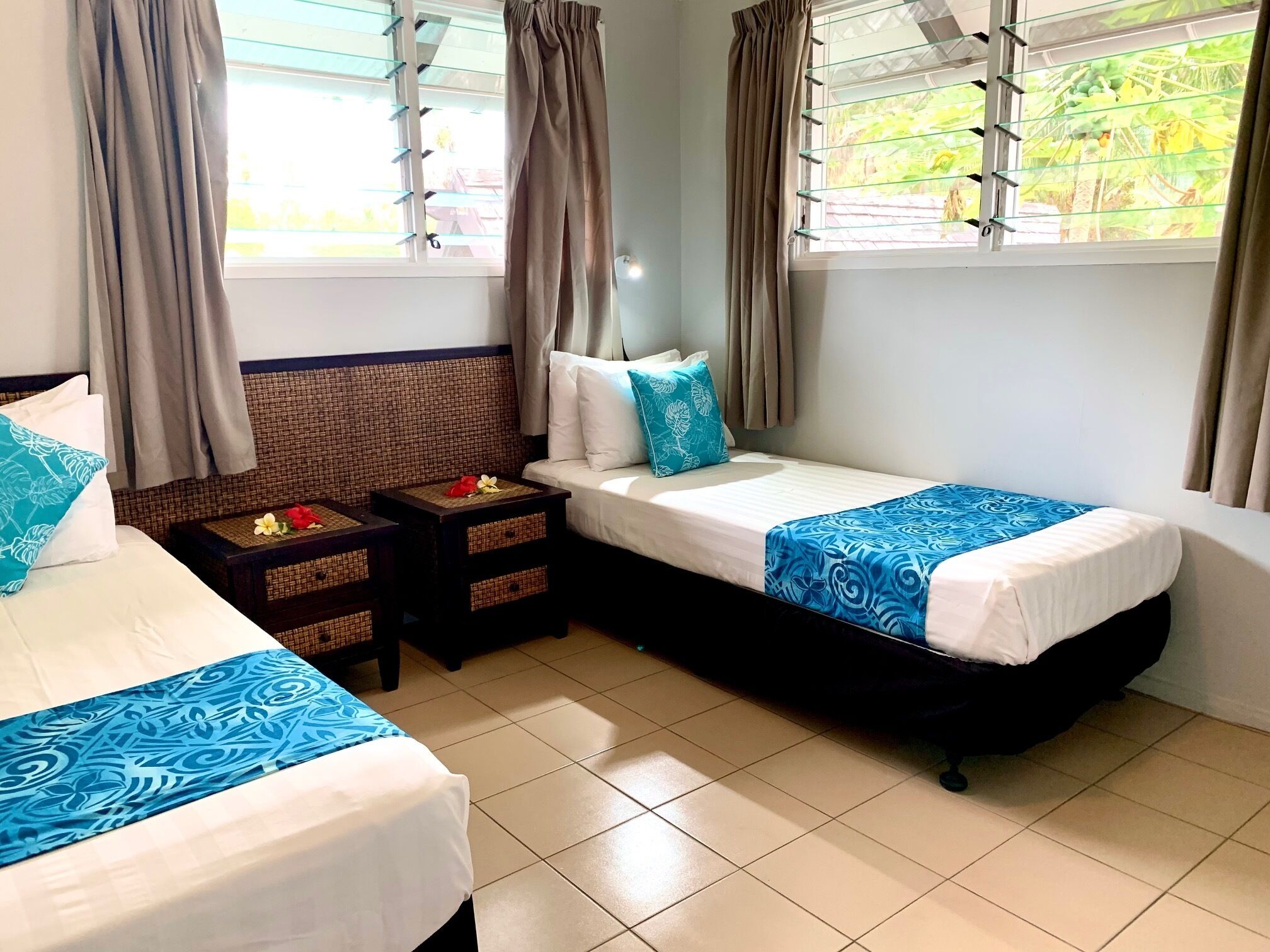 A hotel room with two beds, a sofa, and a window with blinds.