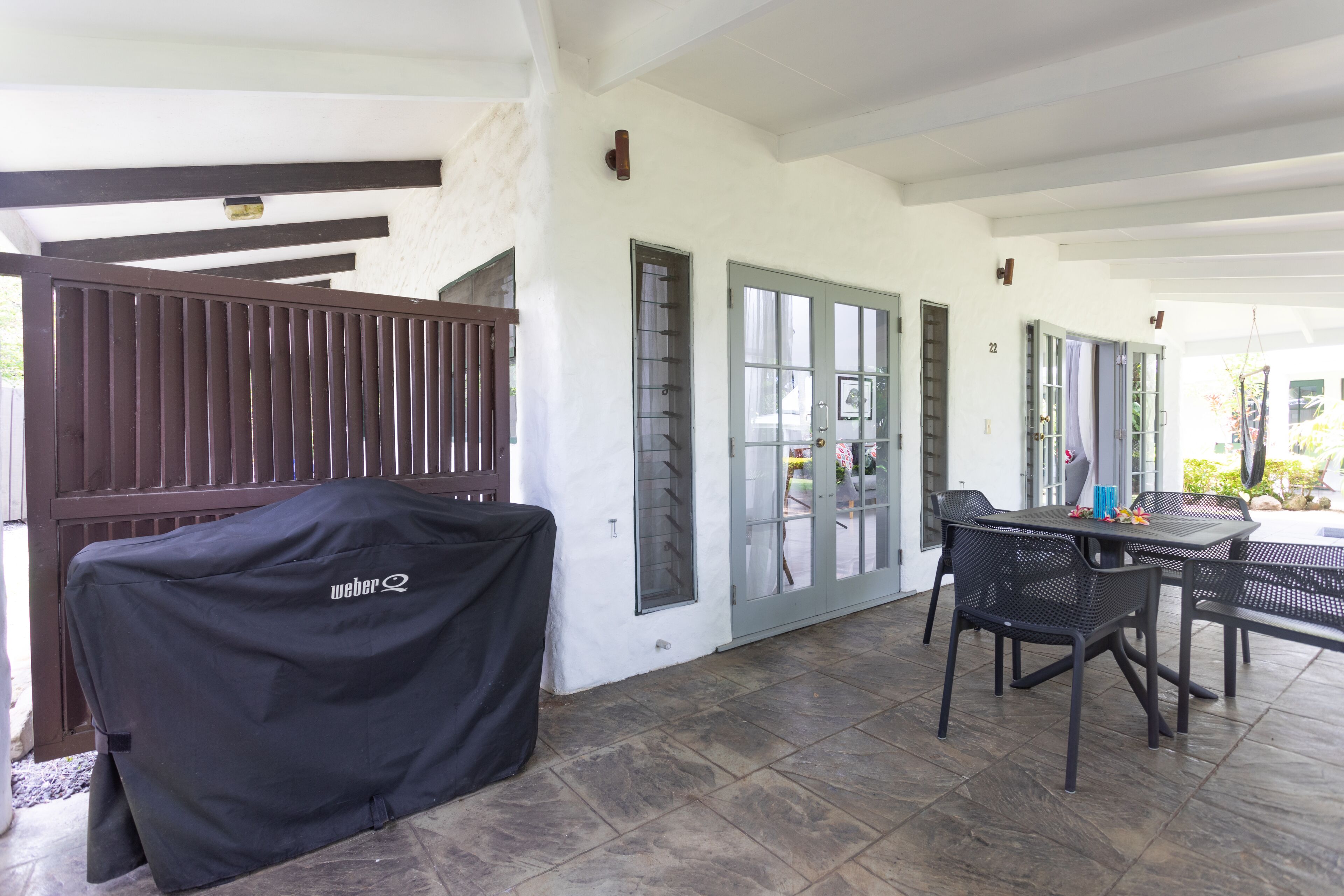 An outdoor patio area with a covered grill, a table with chairs, and a door with a window.