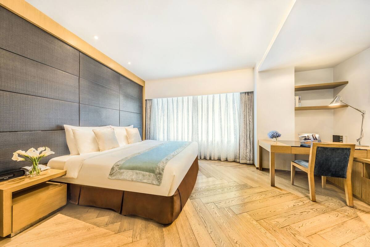 Ett modernt hotellrum med en stor säng, ett skrivbord i trä och utsikt över omgivningarna.