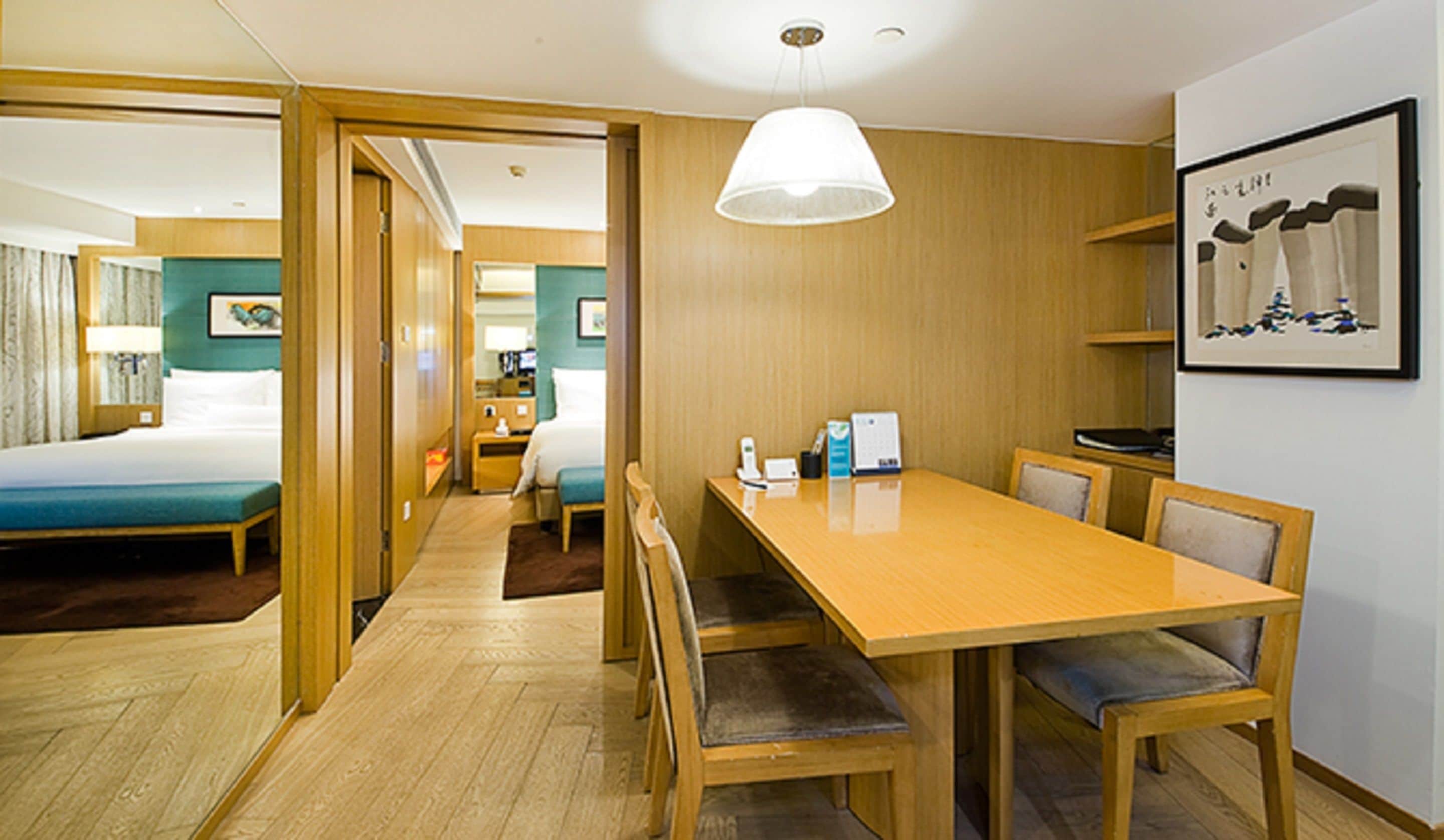 A hotel room with a bed, a desk, and a dining area.