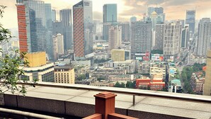 Terraza en la azotea con mesa lista para cenar, una botella de vino y vistas a un horizonte urbano.