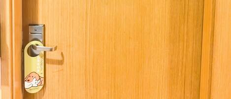 Una puerta de madera con un adhesivo de gato y un timbre con un adhesivo de perro.