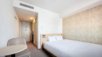 Une chambre d’hôtel avec un lit simple, une petite table et une chaise.
