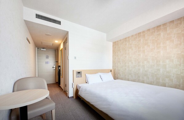 Ein Hotelzimmer mit einem Einzelbett, einem kleinen Tisch und einem Stuhl.