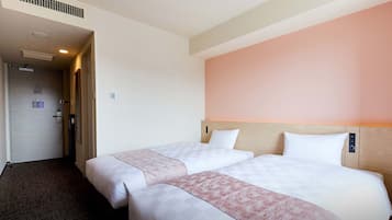 Ett hotellrum med två sängar, en sänggavel i trä och en enkel vägg.
