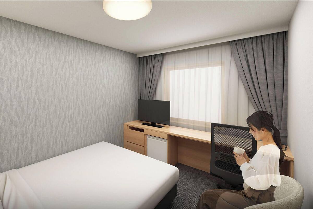 A hotel room with a bed, a desk, a television, and a chair.