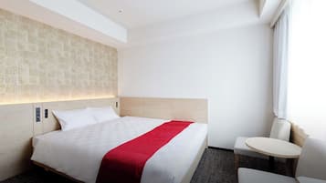 A hotel room with a bed, bedside table, and a small round table.