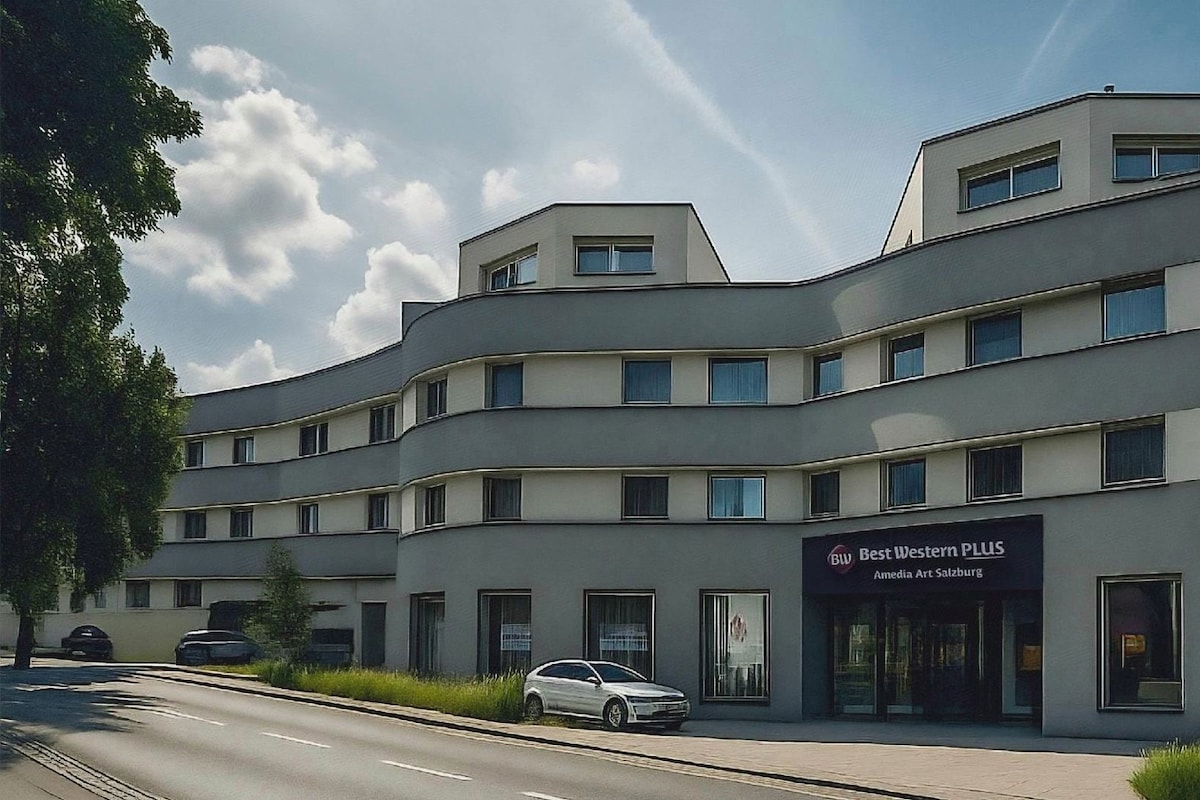 Un edificio de varios pisos con un diseño arquitectónico moderno, que presenta un letrero destacado de 'Best Western PLUS' y un automóvil estacionado en la parte delantera.