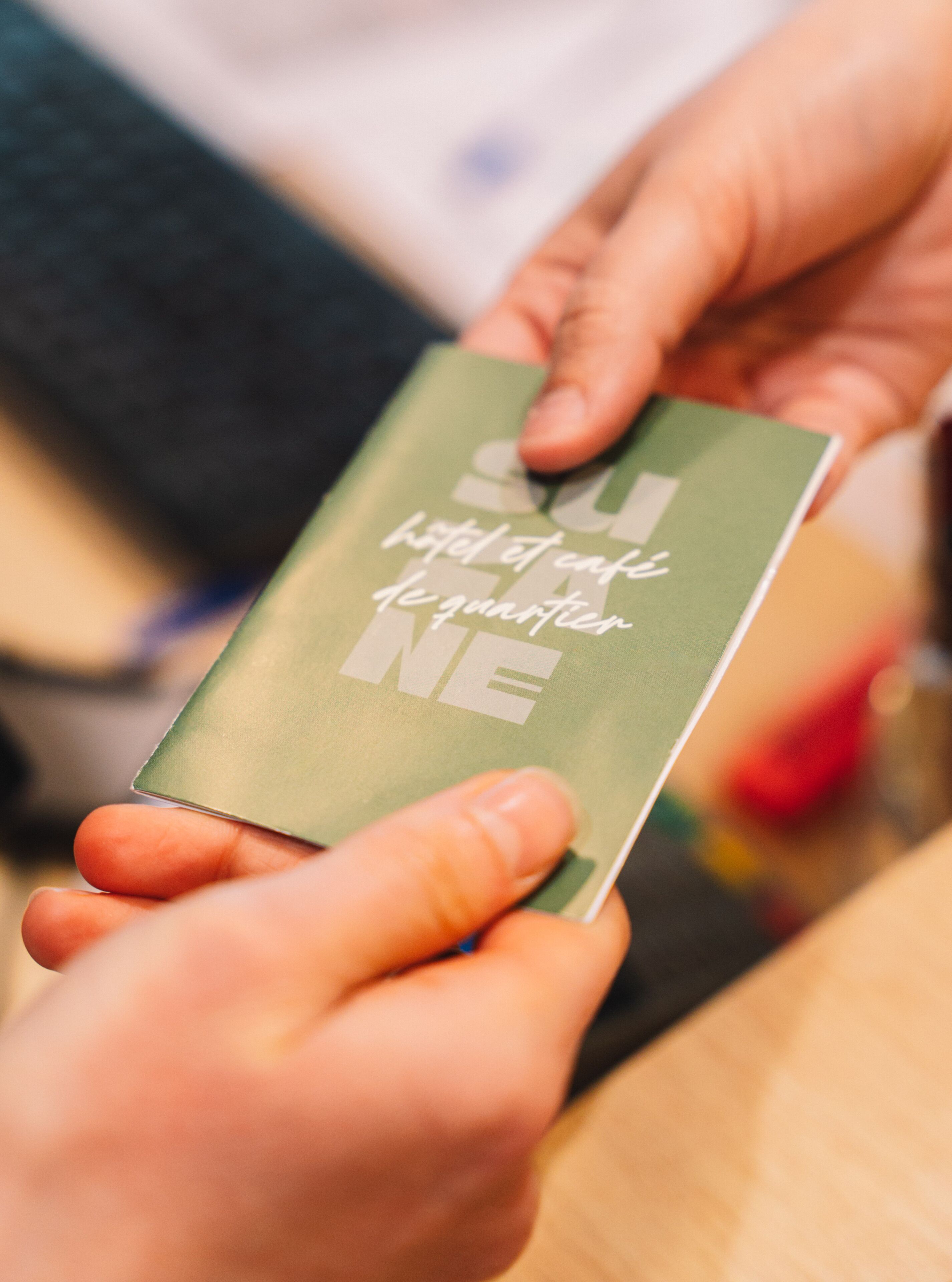 A person holding a green booklet with text on it.