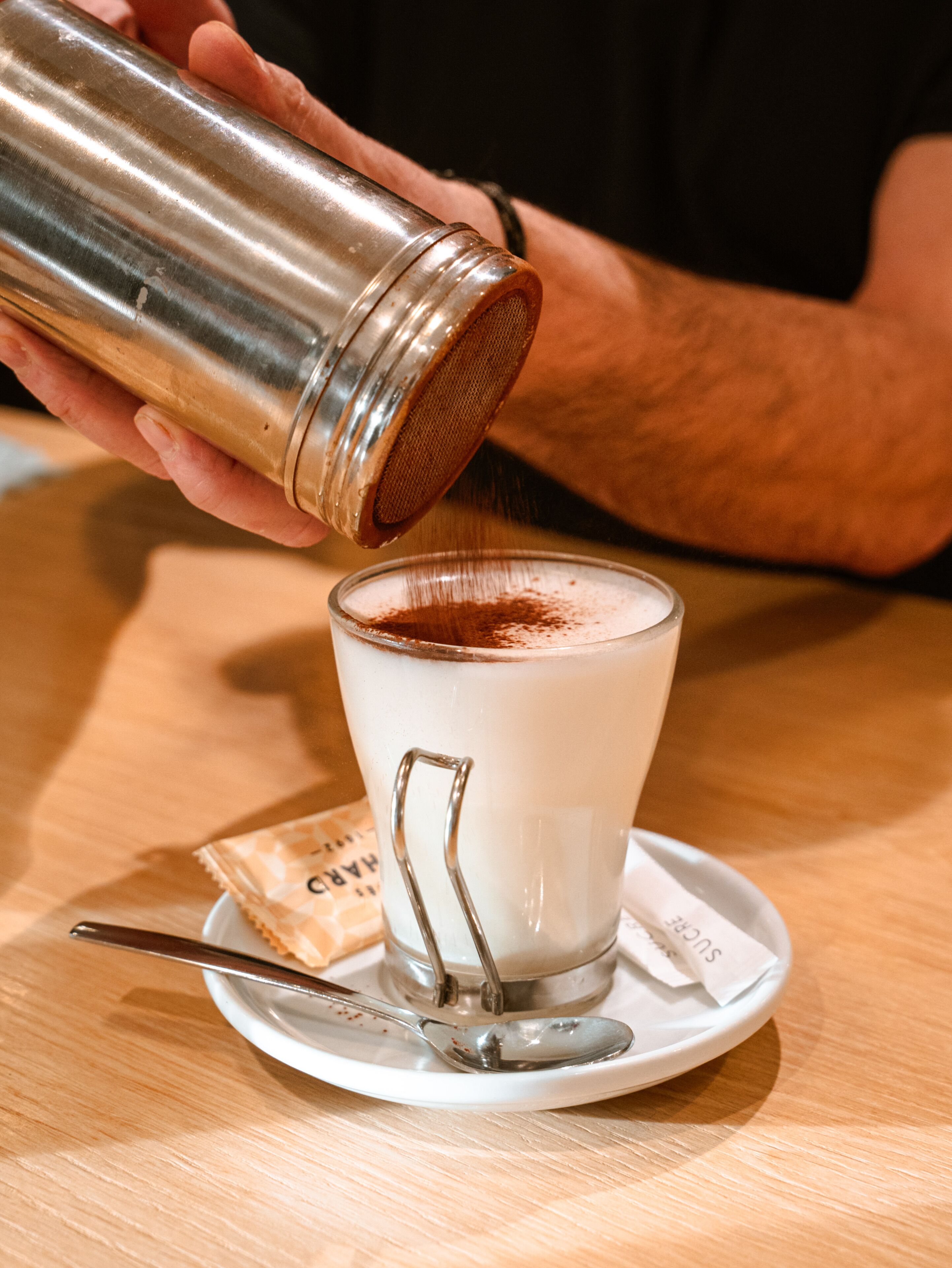 Una persona vertiendo una bebida en un vaso con un colador metálico.