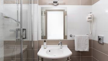 Une salle de bain moderne avec une douche à parois de verre, un lavabo avec un miroir au-dessus et un porte-serviettes.