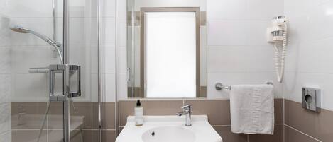 A modern bathroom with a glass-enclosed shower, a sink with a mirror above it, and a towel rack.