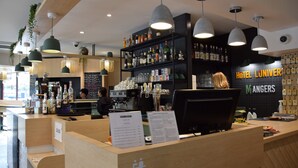 A hotel bar area with a counter, shelves of bottles, and hanging lights.