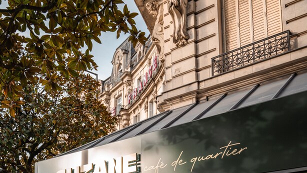 A cafe named 'Suzanne' with outdoor seating and a glass facade.