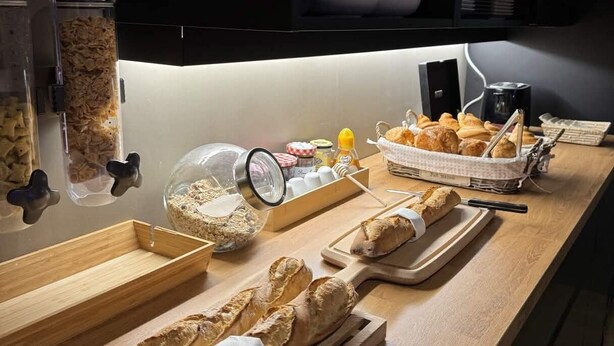 A breakfast buffet with bread, pastries, and condiments. - Cit'Hôtel l'Europe (Cholet)