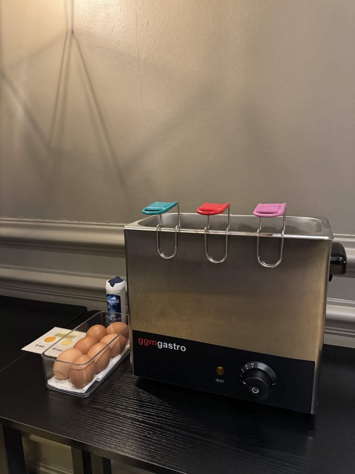 A kitchen with a stainless steel appliance labeled 'ggm gastro' and a tray of eggs on a black countertop.