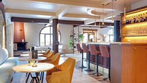 Un espace bar moderne avec des tables rondes et des tabourets de bar, une cheminée et une vue sur l’extérieur.