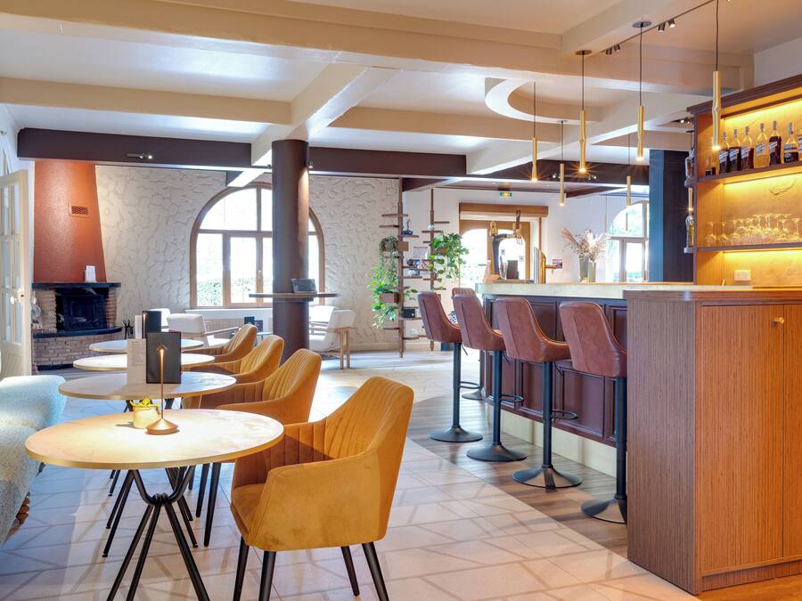 Un área de bar moderna con mesas redondas, taburetes de bar, chimenea y vistas al exterior.