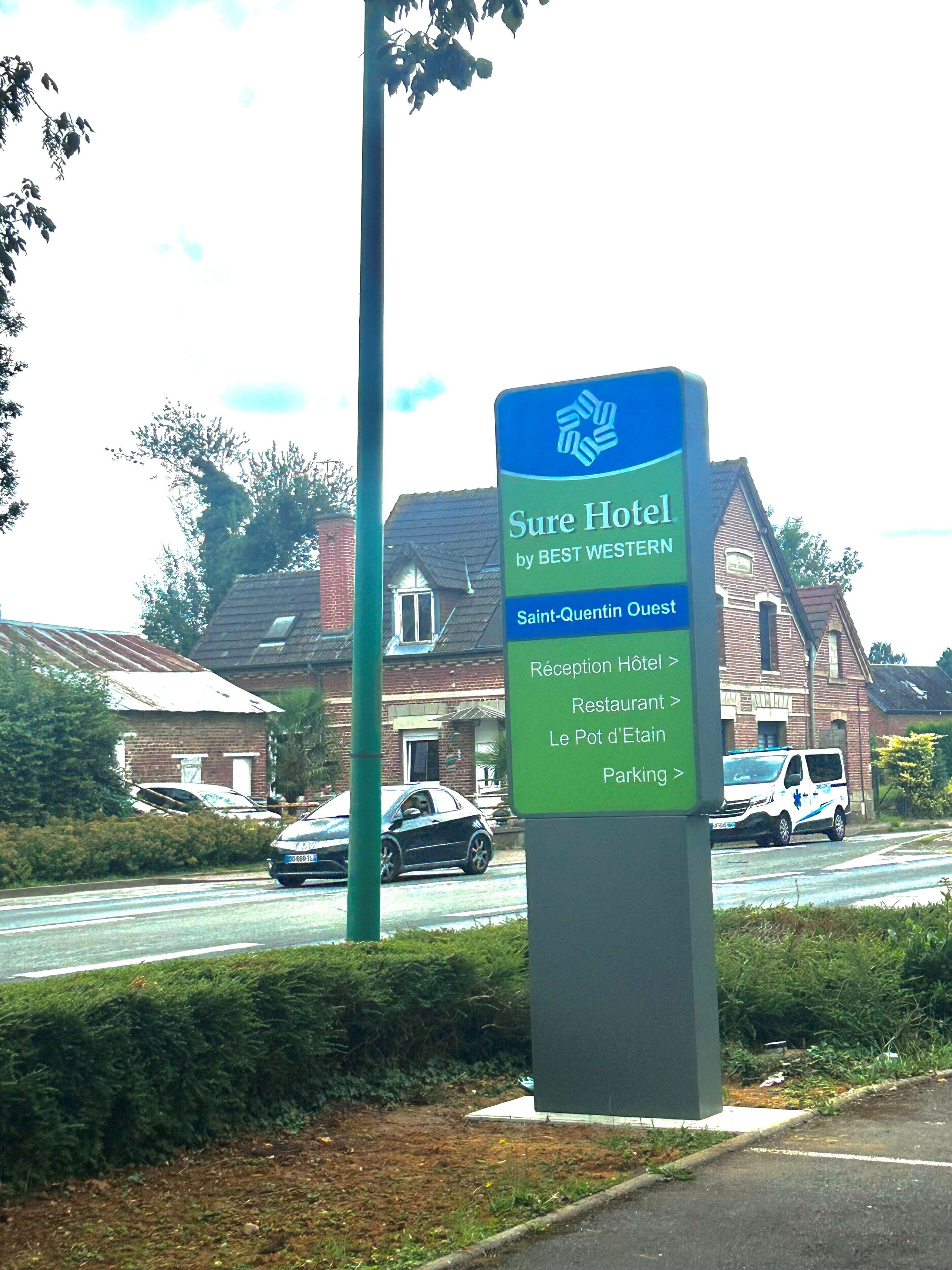 A sign for Sure Hotel by Best Western, indicating amenities like a reception, restaurant, and parking.