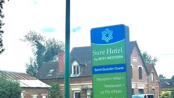 A sign for Sure Hotel by Best Western, indicating amenities like a reception, restaurant, and parking.