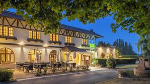 Un hôtel de style architectural européen traditionnel, doté d’une cour intérieure avec des espaces de détente en plein air et d’une entrée bien éclairée.