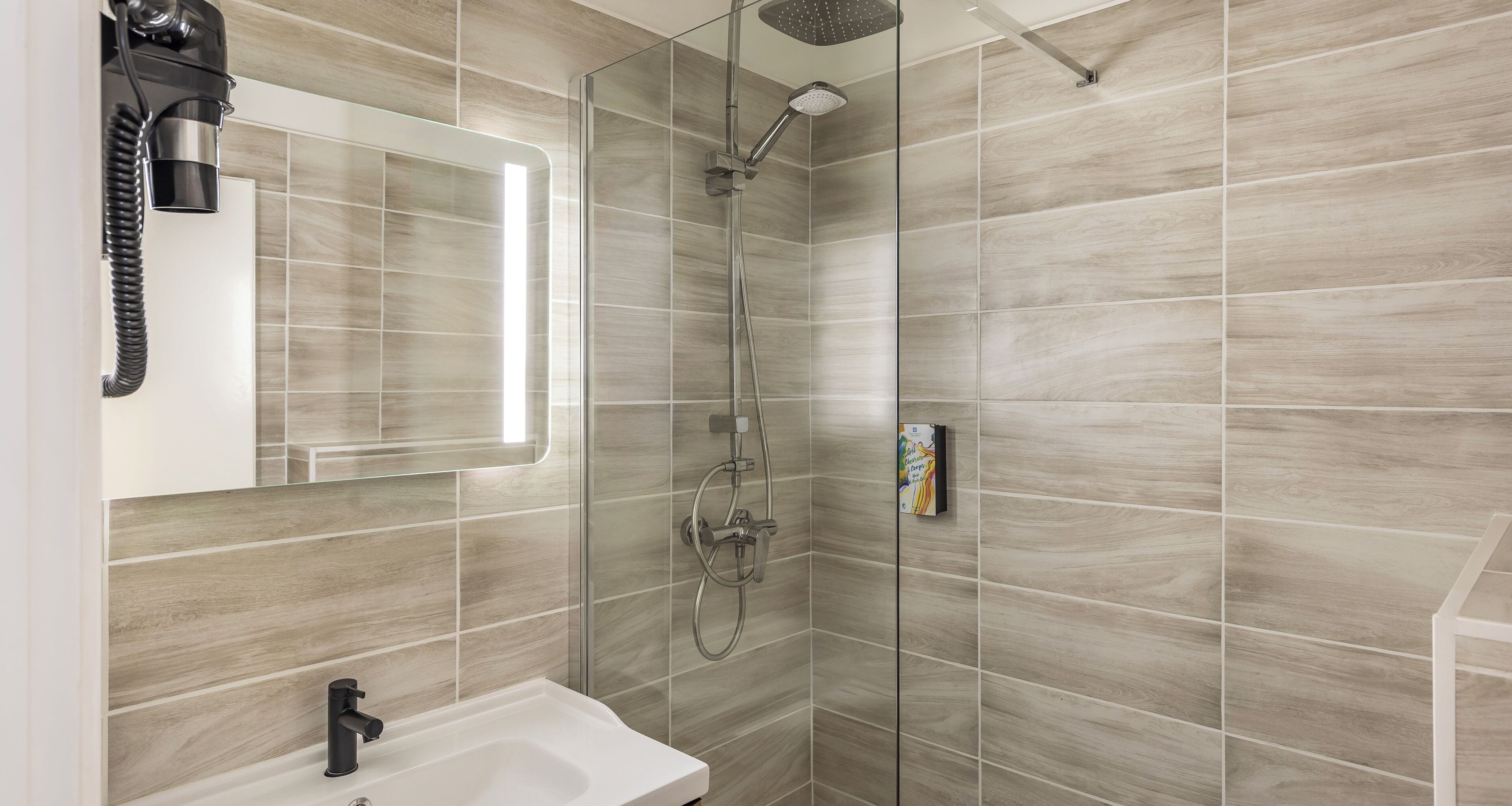 A modern bathroom with a glass shower enclosure, a white sink, and a handheld showerhead.