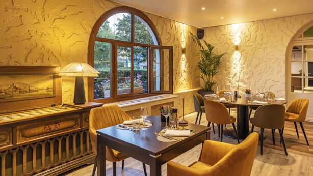 Un espace repas agrémenté d’un mur en marbre, d’une grande fenêtre et d’une table dressée pour quatre personnes.