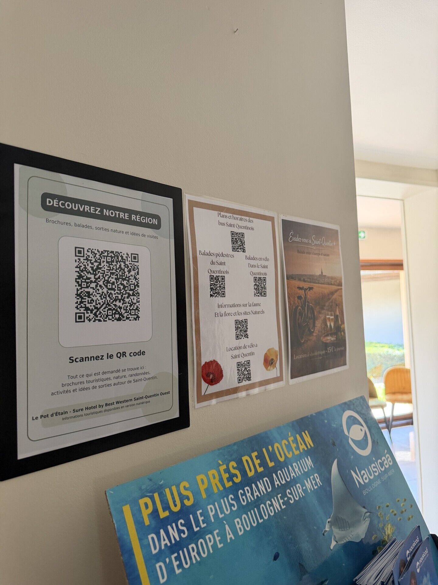 A wall with three informational posters, each featuring QR codes for digital content.