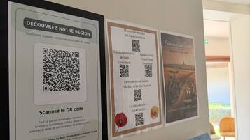 A wall with three informational posters, each featuring QR codes for digital content.