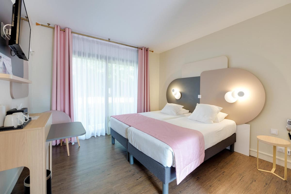 A modern hotel room with a large bed, a desk, and a chair.